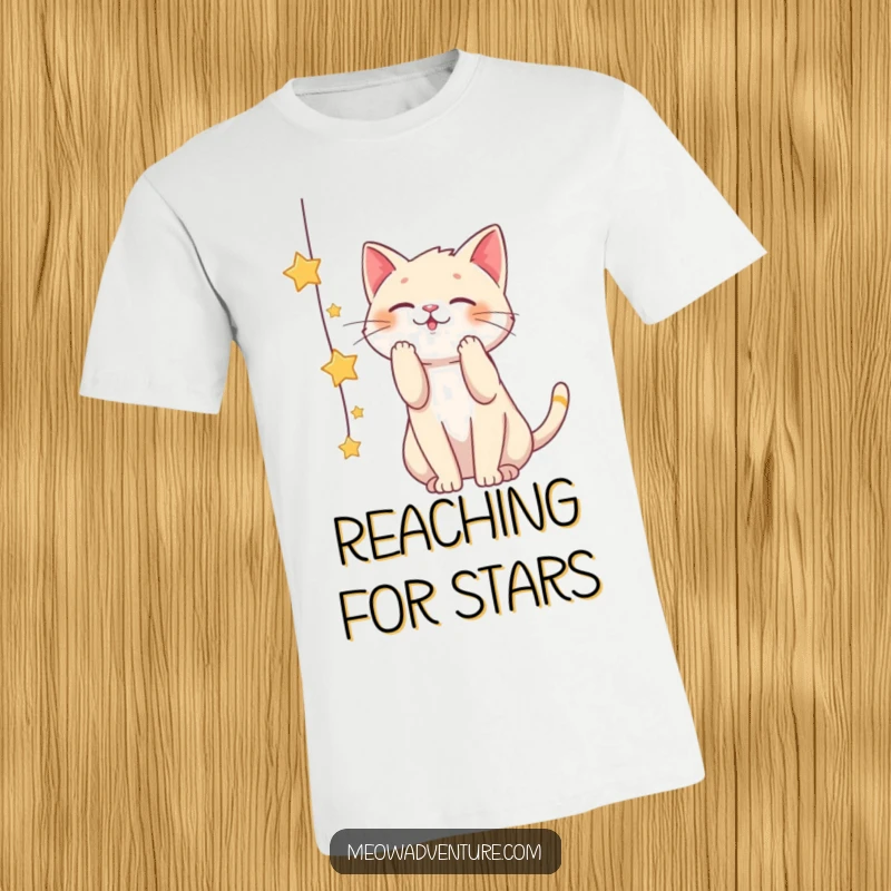 Funny t-shirt featuring a mischievous cat playfully batting at a dangling string of stars, representing aspiration and childlike wonder.